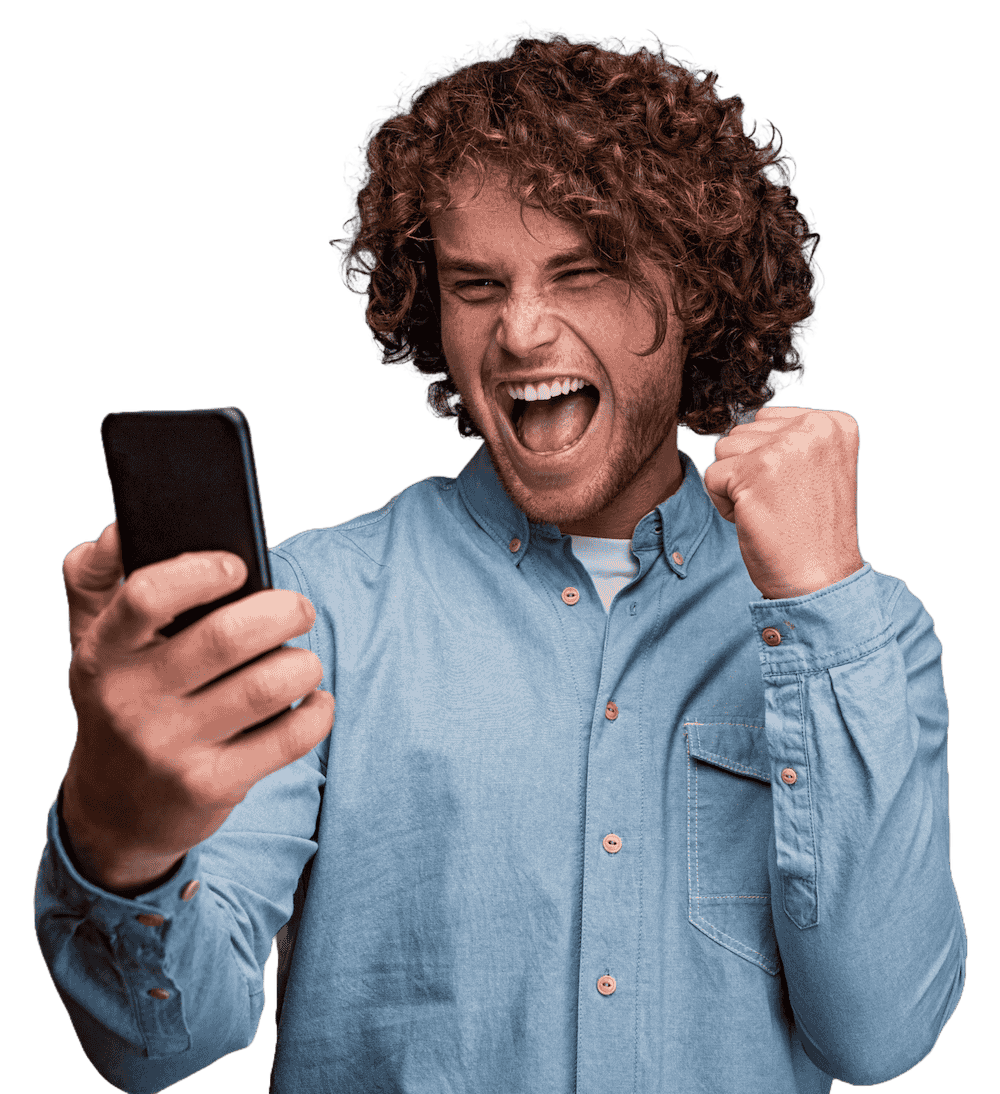 IMG-DDUFZDG.png Excited man with curly hair cheering while looking at his phone.