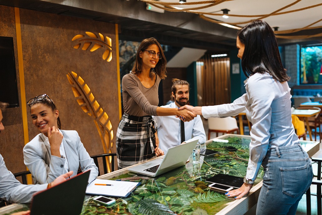 Two women shaking hands in a modern office meeting